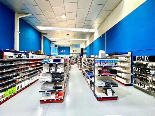 Imagen de interior de almacén con pasillos de paredes azules y estantes con productos