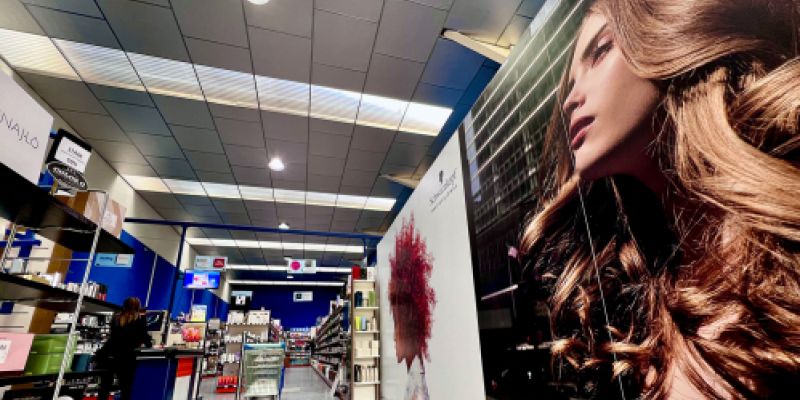 Imagen de interior de almacén con estantes con productos y pared con imagen de peluquería en vinilo